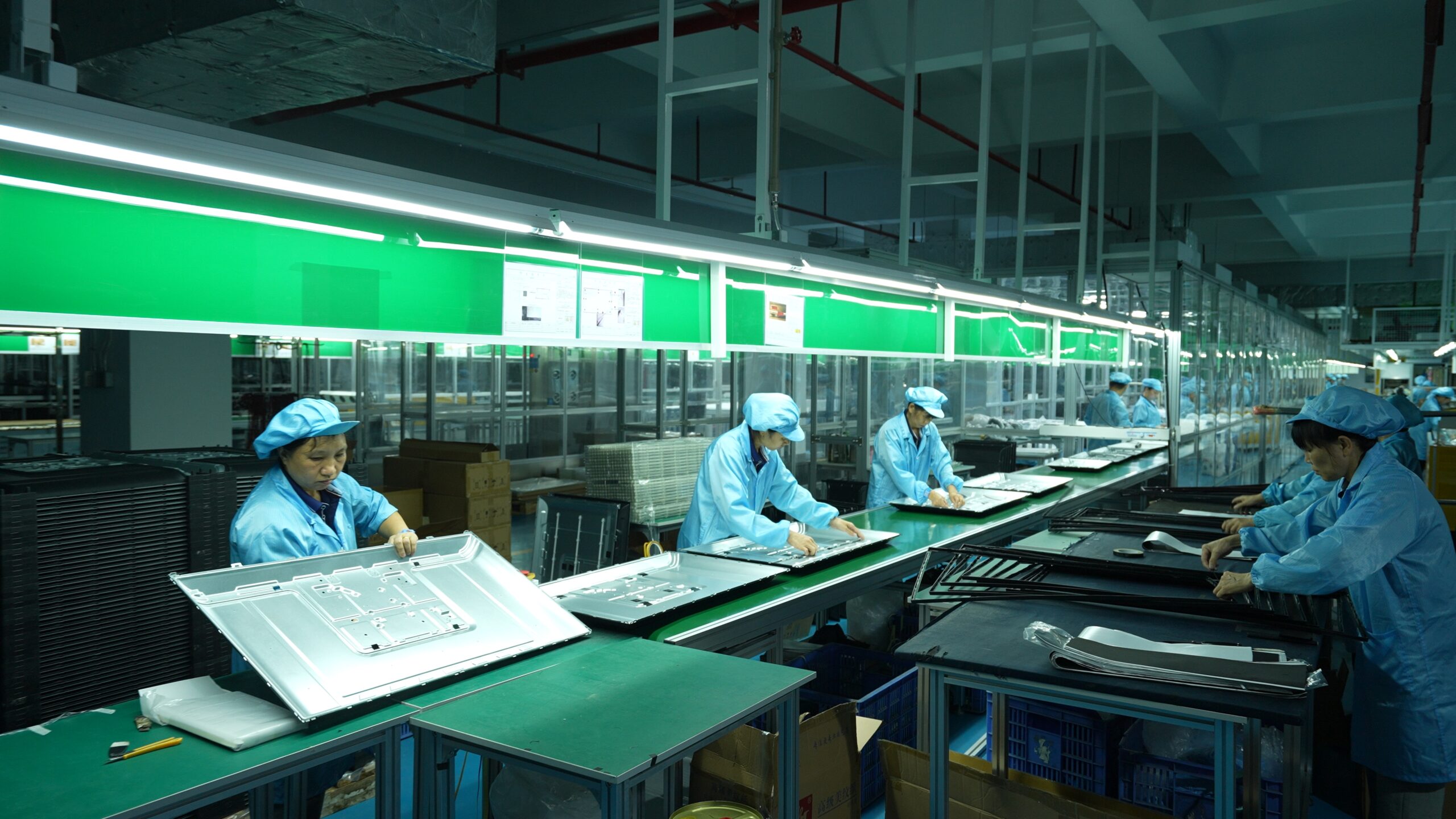 Workers assembling television cabinets at a workshop station